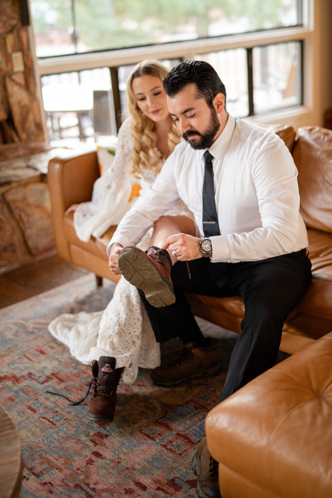 groom helping his bride tie her hiking boots