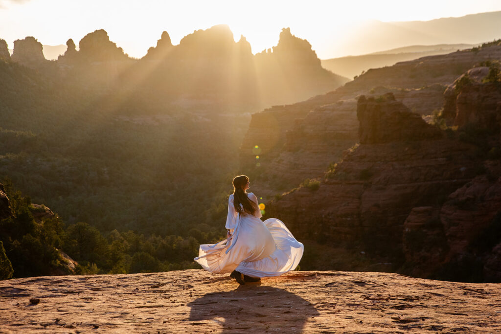 bridal portrait with dress flowing in the air with dramatic sedona landscapes in the backdrop