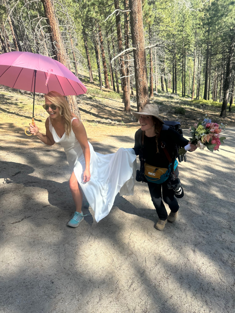 photographer helping the bride during a hike