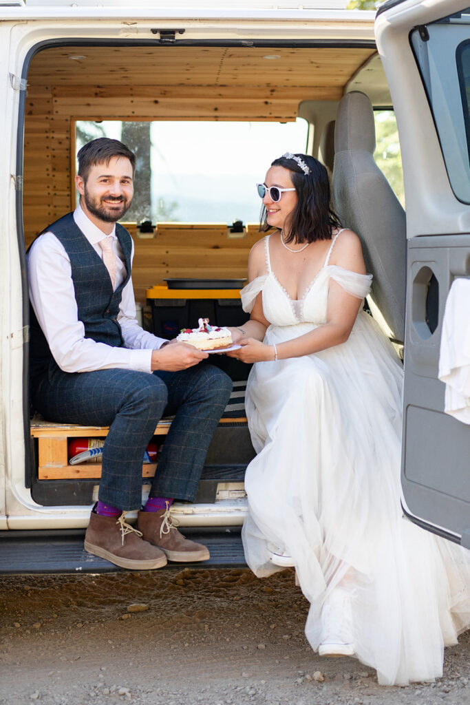 bride and groom cutting and eating their elopement cake in their camper van