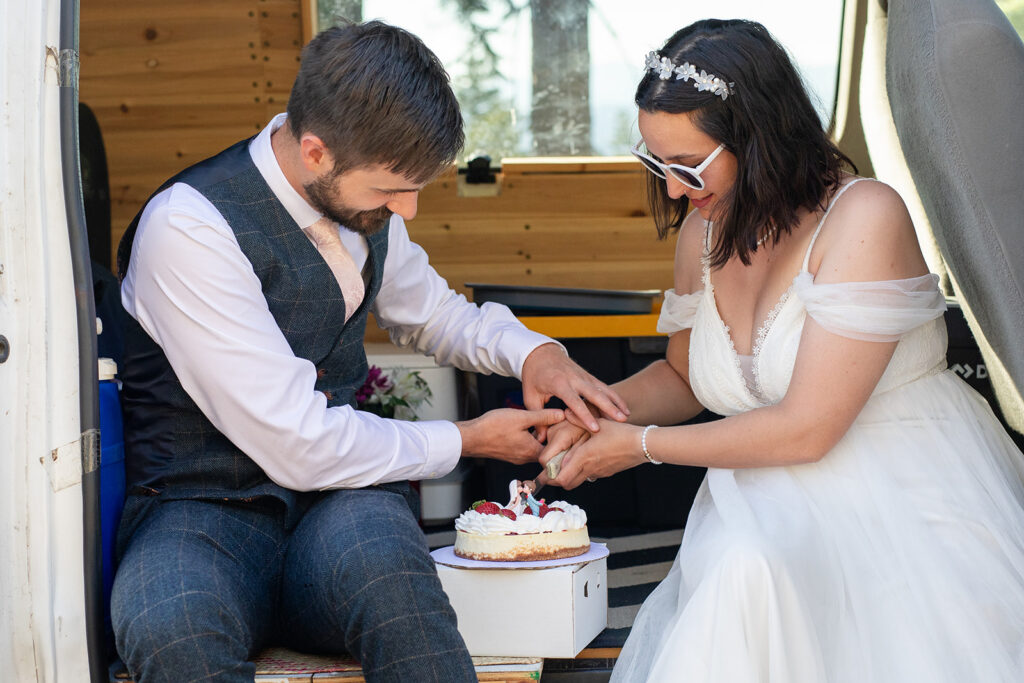 bride and groom cutting and eating their elopement cake in their camper van