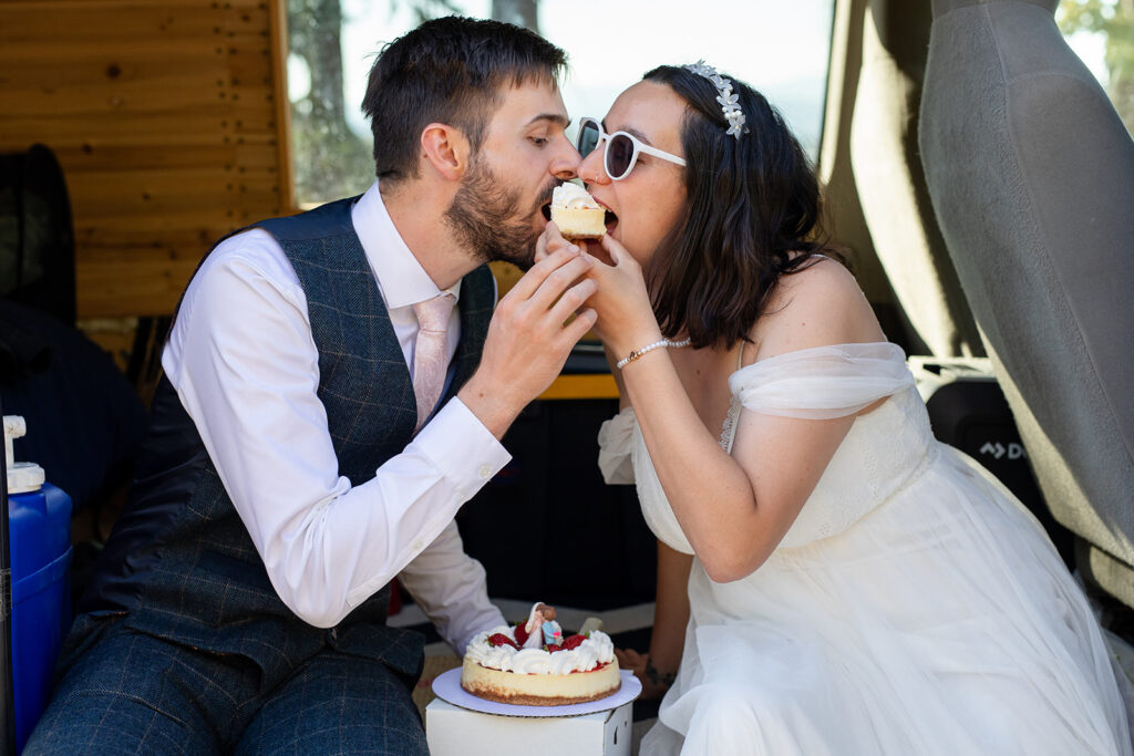 bride and groom cutting and eating their elopement cake in their camper van