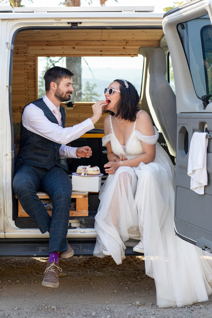 bride and groom cutting and eating their elopement cake in their camper van