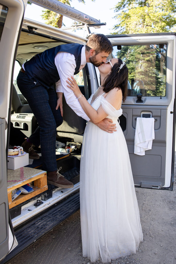 bride and groom cutting and eating their elopement cake in their camper van