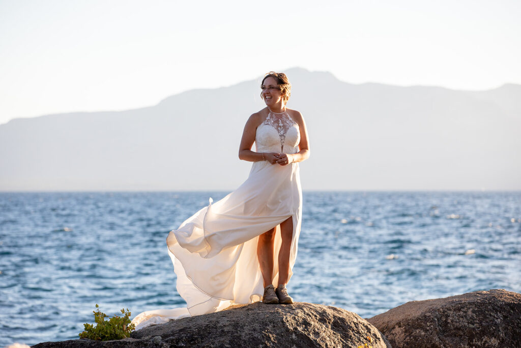 bride standing on a large rock surrounded by water views